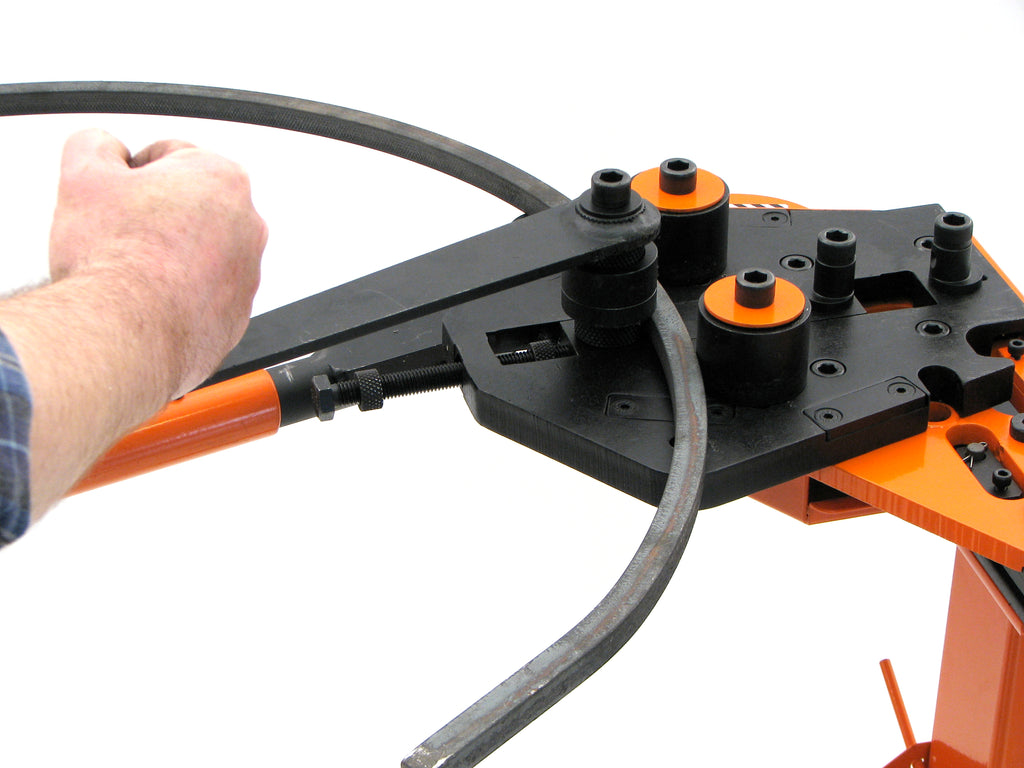 The Metalcraft XL5+ Power Bender allows one to roll arches, curves and rings in flat and square bars by driving steel backwards and forwards through rollers using the winding handle.  (note - be aware that the knurled drive roller can leave a "knurl" pattern impression on the face of the steel bar being rolled)