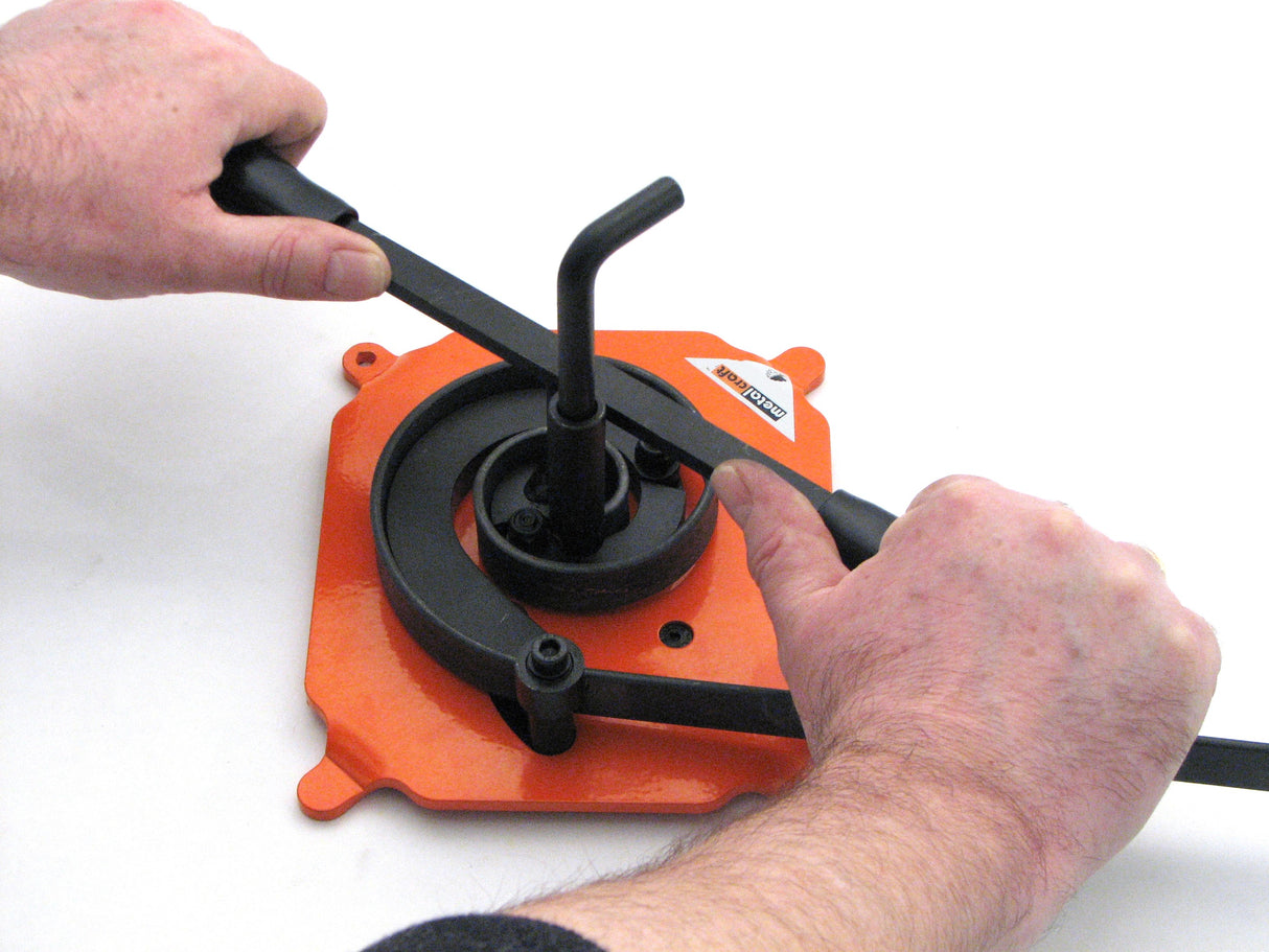 Hands shown turning the top handle on the Metalcraft Scroll Bender MK2/3 Former to form scroll
