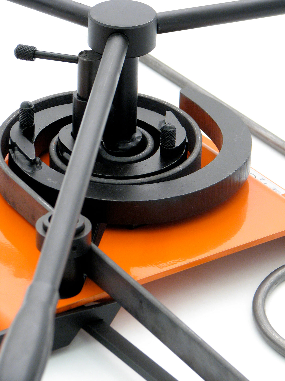 Closeup of flat metal steel strip being scrolled.  In front it shows the metal being held down with the roller on the slide unit.